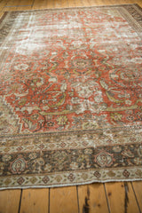 Distressed terra cotta and sand field of a Mahal carpet with intertwined floral motifs.