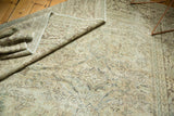 Distressed Mahal carpet with worn ivory, pale blue, green floral patterns, foundation showing.