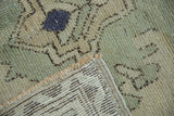 Oushak rug corner close-up revealing distressed pile, secured side, and hand-knotted foundation.