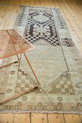 Distressed vintage Oushak runner's end, showing muted beige tones, textured wear, and fringe.