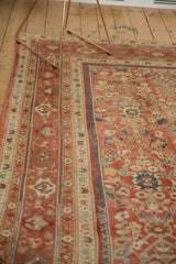 Close-up of antique Mahal carpet's terra cotta field featuring germinating plant motifs.