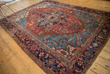 Detail of vintage Heriz carpet showing dark blue border, madder red field, and secured fringe.