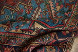 Folded vintage Heriz carpet, showcasing hand-knotted texture, madder red, and sky blue geometric motifs.