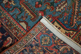 Folded corner of a vintage Heriz rug, showing hand-knotted fringe and dense foundation.