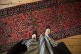 Looking down at the deep blush field of a vintage Lilihan runner with floral and boteh motifs.