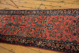 Angled view showcasing the allover floral pattern and navy border of the vintage Lilihan rug runner.