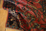 Folded vintage Persian rug showing its rich texture, navy botehs, and blush floral motifs.