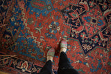 Bold madder red field of antique Heriz with navy, sapphire blue, green plant motifs.