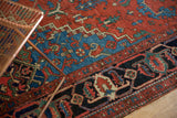 Antique Heriz rug's rich madder root red, navy blue, and mallard green patterns, displaying even wear.