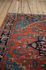 Antique Heriz carpet's geometric field with madder red, navy, and sapphire blue plant motifs.
