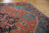 Antique Heriz carpet: madder red field, navy blue geometric border, and ivory fringe.
