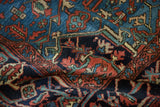 Intricate hand-knotted Heriz rug pile detail showing madder red and navy plant motifs.