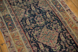 Close-up: Antique Malayer rug's navy field, halved medallion, pale pink paisley, storied texture.