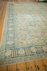 Distressed vintage Tabriz rug with faded sky blue motifs on an antique ivory field.