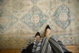 Distressed Sivas carpet showing denim blue lattice, ivory ground, faded floral details, and even wear.
