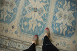 Hand woven Soumac carpet detailed with slate blue, ivory geometric patterns, shown underfoot.