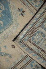 Folded Soumac carpet with flat weave texture, showcasing ivory, slate blue, and brown patterns.