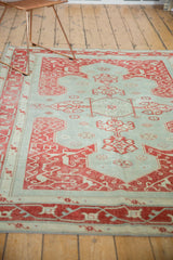 Distressed Oushak rug corner with faded cherry red elaborate vinery on powder blue.