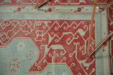 Distressed vintage Oushak rug detail: faded cherry red spandrel with powder blue vinery motif.