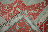 Distressed vintage Oushak rug folded corner showing faded red vinery and numbered reverse.