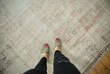Distressed Oushak rug's textured pile, featuring visible foundation and soft ivory and rose tones.