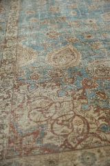 Distressed pile of vintage Tabriz carpet showing faded dusty red, beige, and blue vinery.