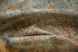 Distressed Tabriz carpet detail: worn scrolling vinery in sapphire blue and dusty wine red.