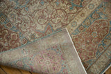 Folded vintage distressed Tabriz carpet, showing worn pile and hand-knotted foundation.
