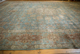 Distressed vintage Tabriz rug featuring faded blue tones, intricate vinery, and ornate cartouche border.