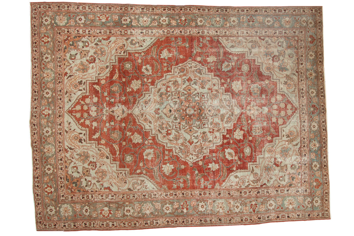 Distressed vintage Khoy carpet with a large brick red medallion on a pale slate blue floral ground.