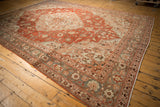Angled view of the vintage distressed Khoy carpet, showing its pale slate blue border and brick red floral field.