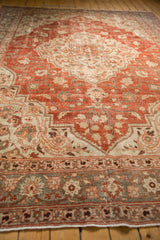 Low angle view of a vintage Khoy carpet, highlighting its distressed low pile and floral design elements.