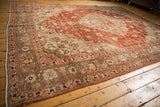 Angled view of the distressed Persian Khoy carpet's intricate floral border and time-softened texture.