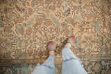Distressed texture and geometric floral design on a Vintage Mehrivan carpet in sandy beige and dusty teal.
