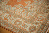Distressed corner of Veece carpet with intricate pale rust and ivory border motifs.