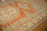 Distressed Veece carpet corner, faded geometric patterns in rust orange and ivory.
