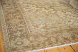Vintage distressed Heriz rug corner with geometric serrated leaf patterns in natural tones.