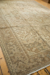 Vintage distressed Heriz carpet corner, showing geometric border, worn fringe, and bronze tones.