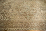 Distressed vintage Heriz carpet displaying geometric serrated leaves and muted bronze tones.