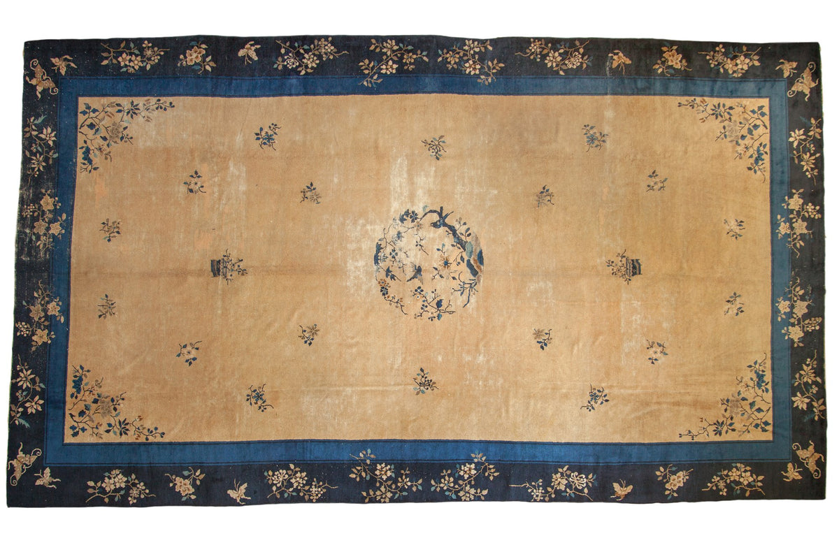 Vintage Peking carpet with a bird medallion, open golden field, and intricate indigo floral borders.