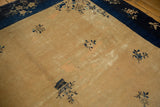 A vintage Peking rug corner with low pile, visible wear, and a rich indigo floral border.