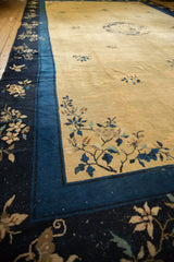 Angled view of a vintage Peking carpet's corner with an indigo border and floral sprays on a gold field.