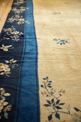 A vintage Peking carpet's indigo floral border and dusty gold field showing even, low pile.