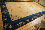Angled perspective on a vintage Peking carpet, showing its deep indigo border and golden floral field.