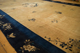 Time-softened low pile texture of a vintage Peking carpet's gold field and contrasting indigo border.