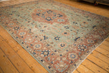 Distressed vintage Tabriz carpet: pale rust medallion on seafoam field with oversized serrated leaves.