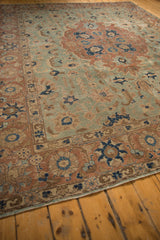 Worn corner of the vintage distressed Tabriz carpet, featuring seafoam green, pale rust, and navy floral motifs.