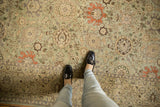 Distressed Tabriz carpet, seafoam green allover floral vinery, beige, terra cotta tones, under loafers.