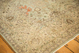 Distressed vintage Tabriz rug's beige border showing faded floral vinery and seafoam field.