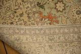 Distressed Tabriz rug pile with seafoam, beige vinery and the visible woven foundation.